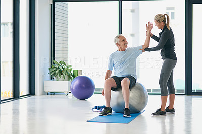 Buy stock photo Full length shot of a friendly female physiotherapist helping her senior patient stretch in a fitness centre