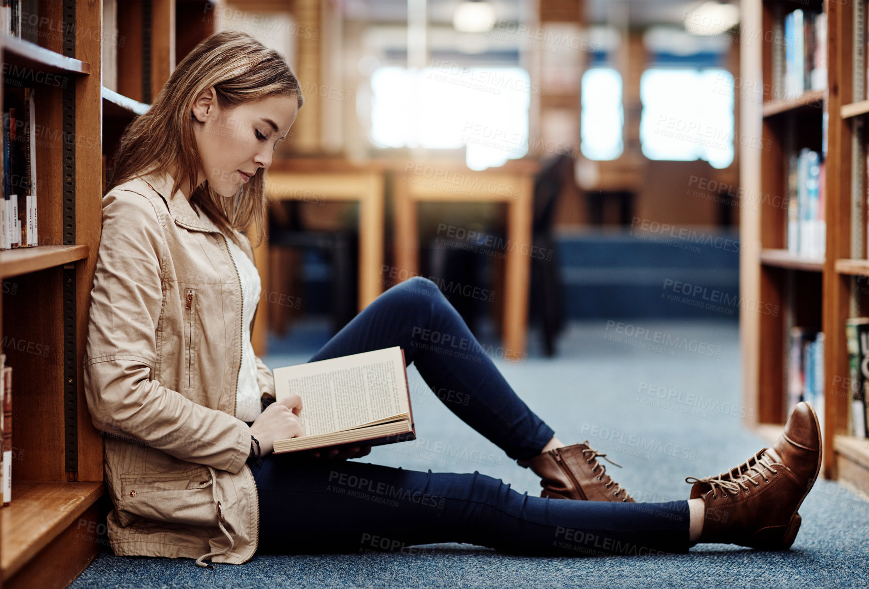 Buy stock photo College student, library and girl reading book for education, studying and literature in English or language. Person relax on floor by shelf with novel, knowledge and scholarship for learning history