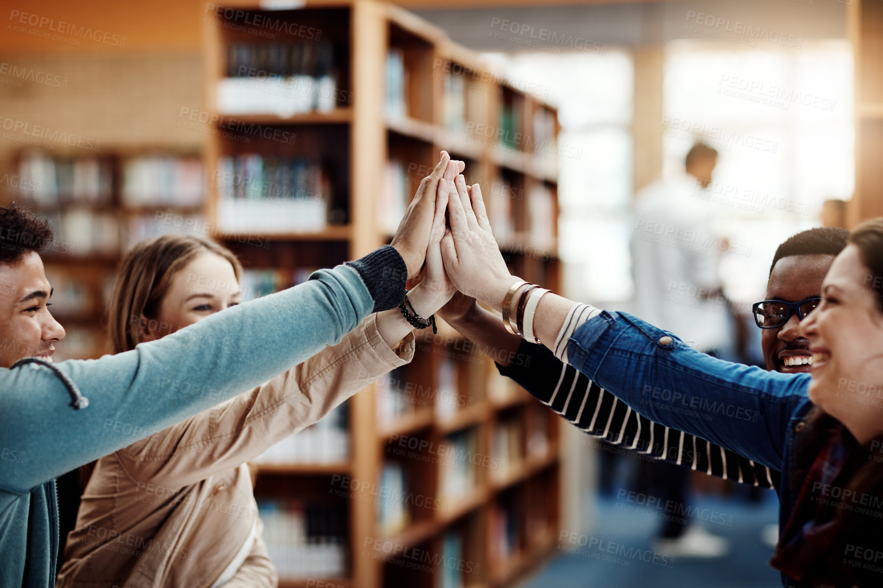 Buy stock photo Students, group and high five in library for education, learning and knowledge goals, support or teamwork. Young people with hands together for motivation, collaboration and success in university