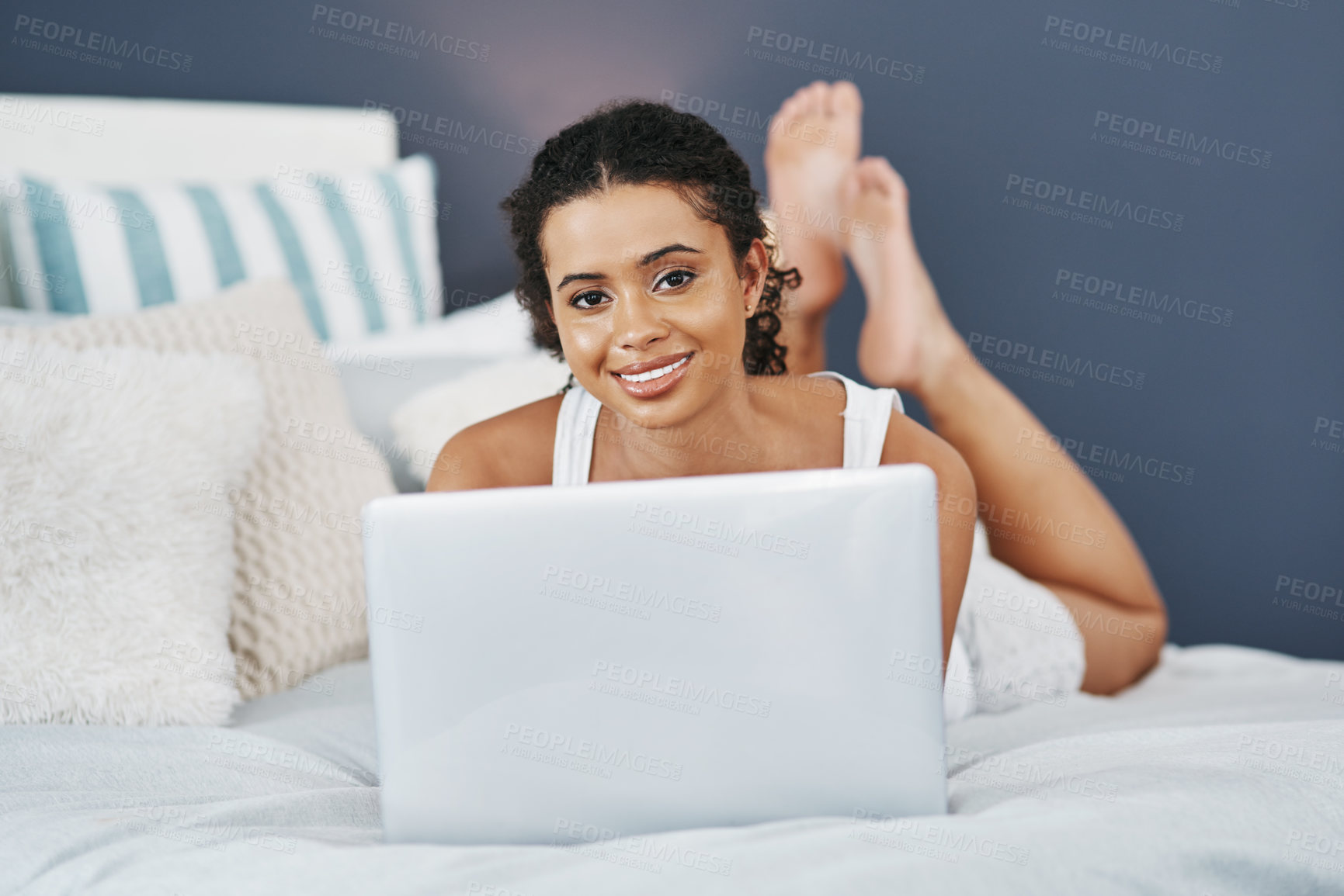 Buy stock photo Shot of an attractive young woman using her laptop while relaxing on her bed at home