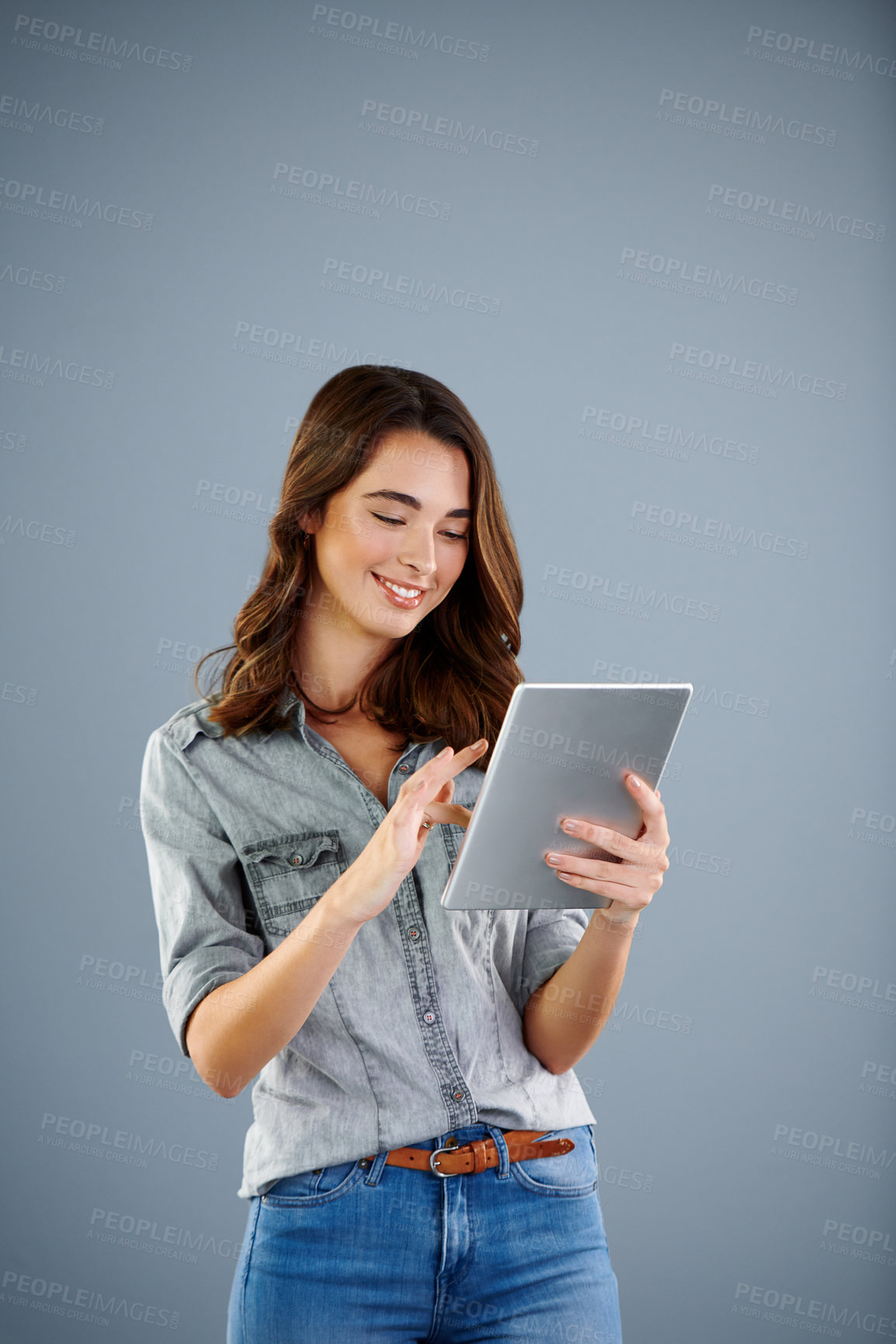 Buy stock photo Studio shot of an attractive young woman using her digital tablet against a grey background