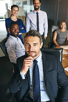 Buy stock photo Shot of a businessman sitting in an office with colleagues in the background