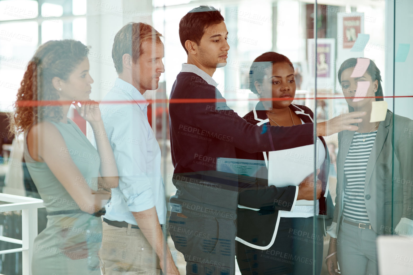 Buy stock photo Cropped shot of a group of businesspeople strategizing on a glass wipe board in their office