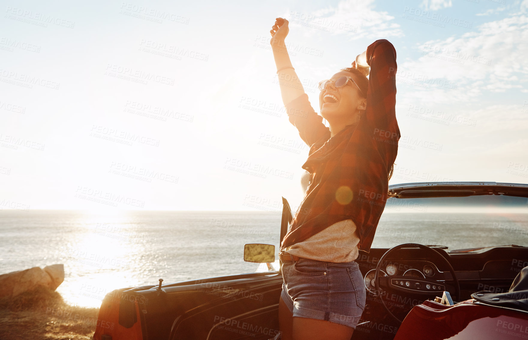 Buy stock photo Shot of a happy young woman enjoying a summer’s road trip