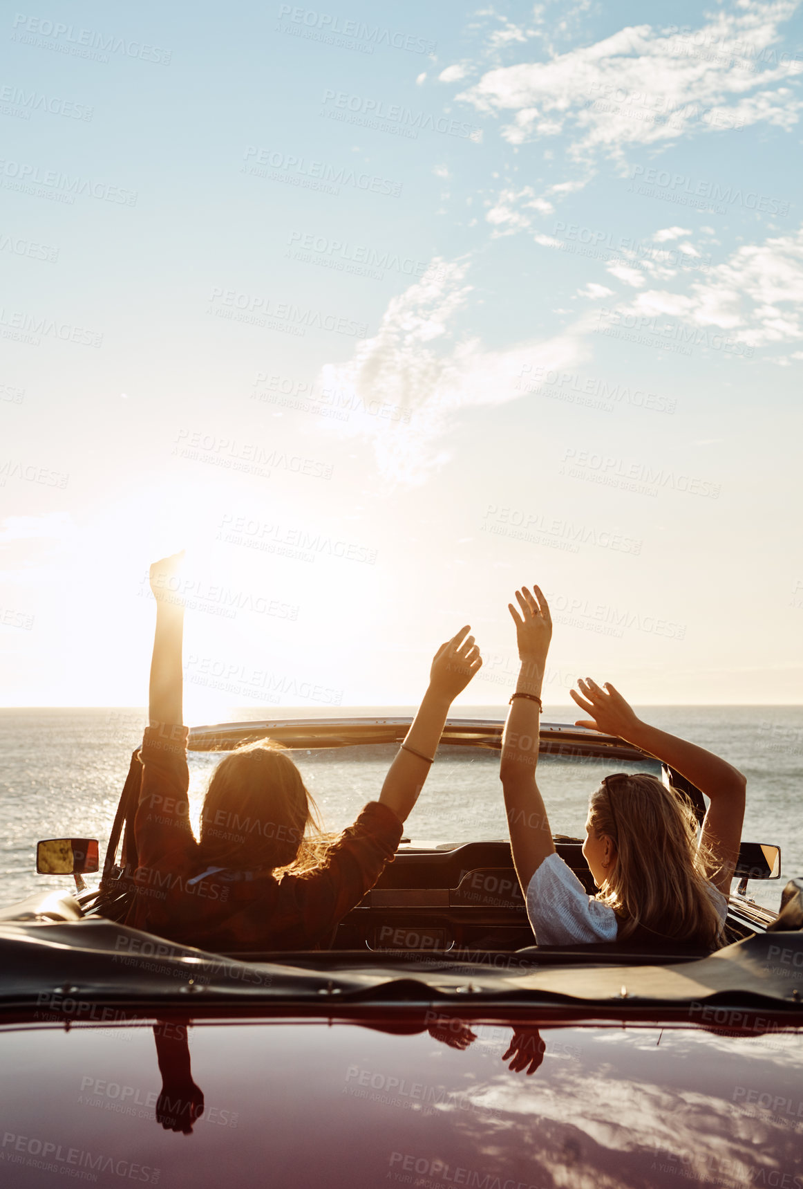 Buy stock photo Shot of a two happy young women enjoying a summer’s road trip together