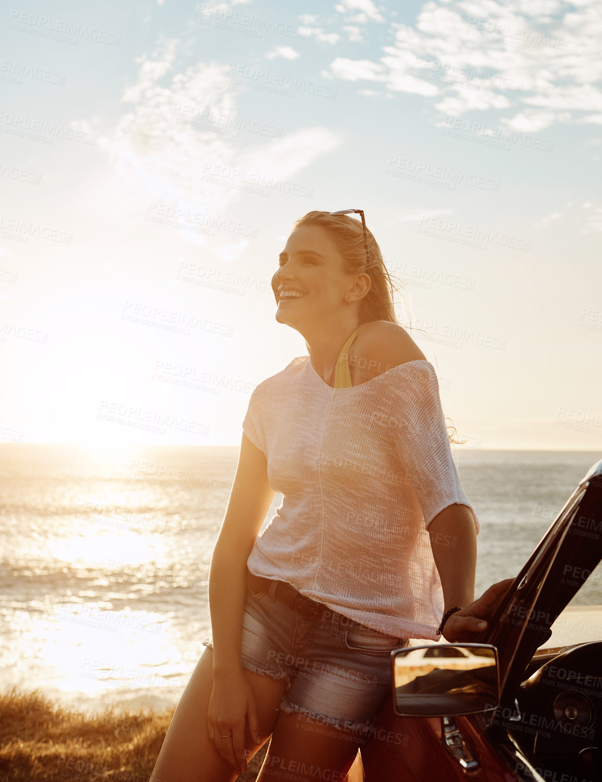 Buy stock photo Shot of a happy young woman enjoying a summer’s road trip