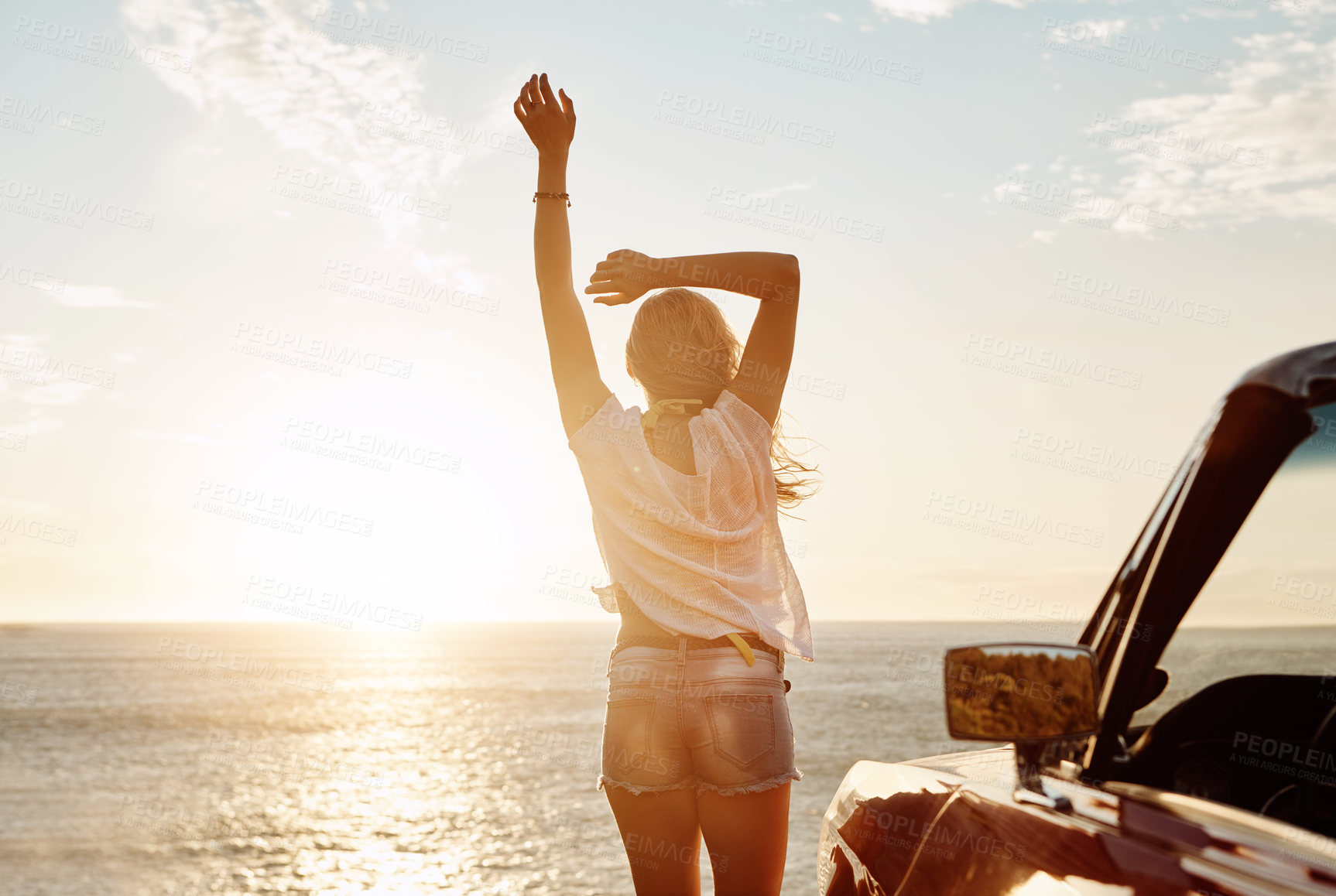 Buy stock photo Shot of a happy young woman enjoying a summer’s road trip