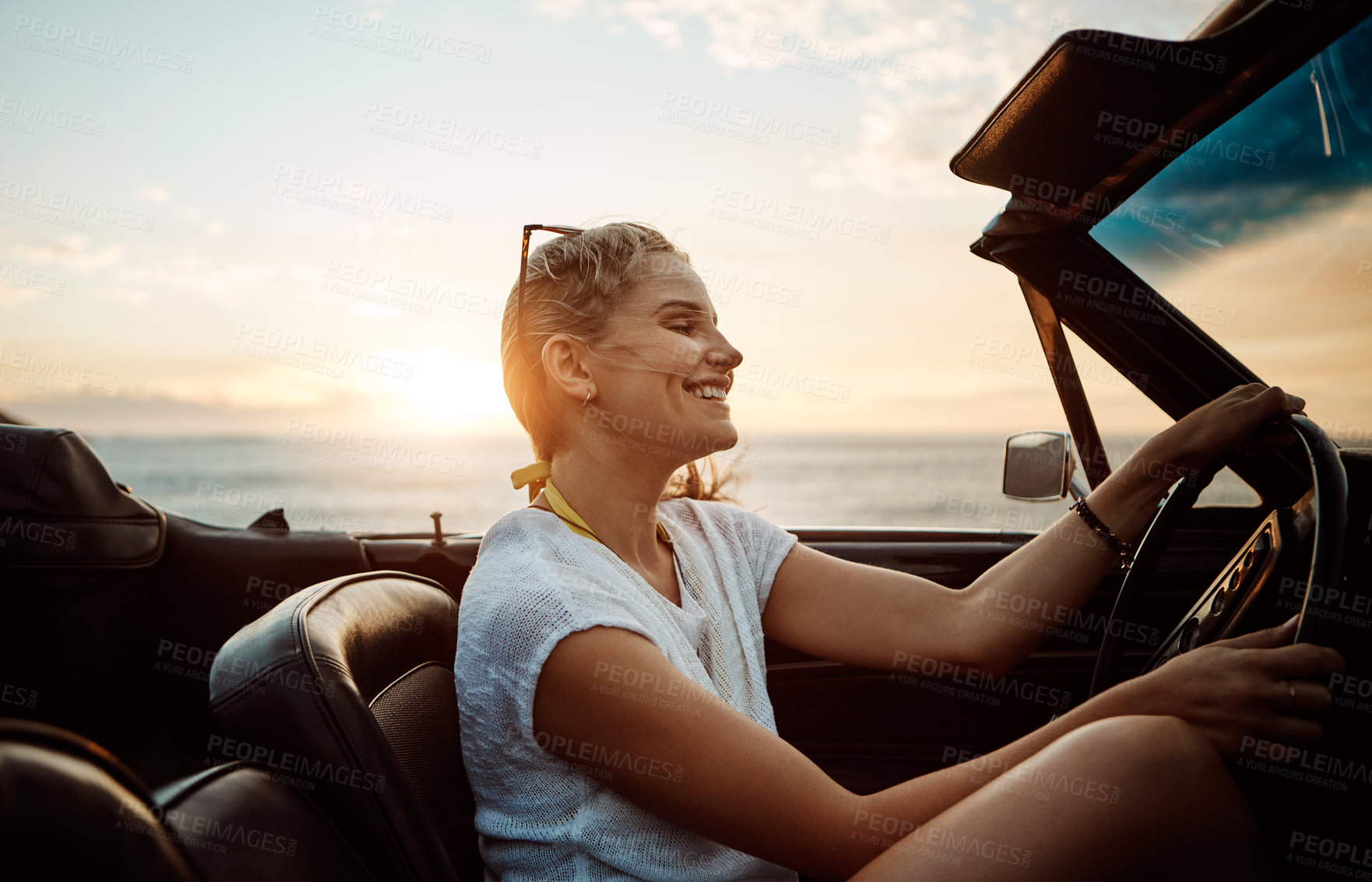 Buy stock photo Shot of a happy young woman enjoying a summer’s road trip