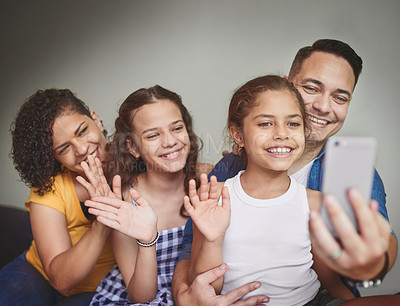 Buy stock photo Shot of a family of four video calling using a cellphone