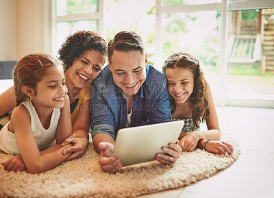 Buy stock photo Shot of a family of four using a digital tablet while relaxing at home