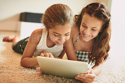 Buy stock photo Shot of two young girls using a digital tablet at home