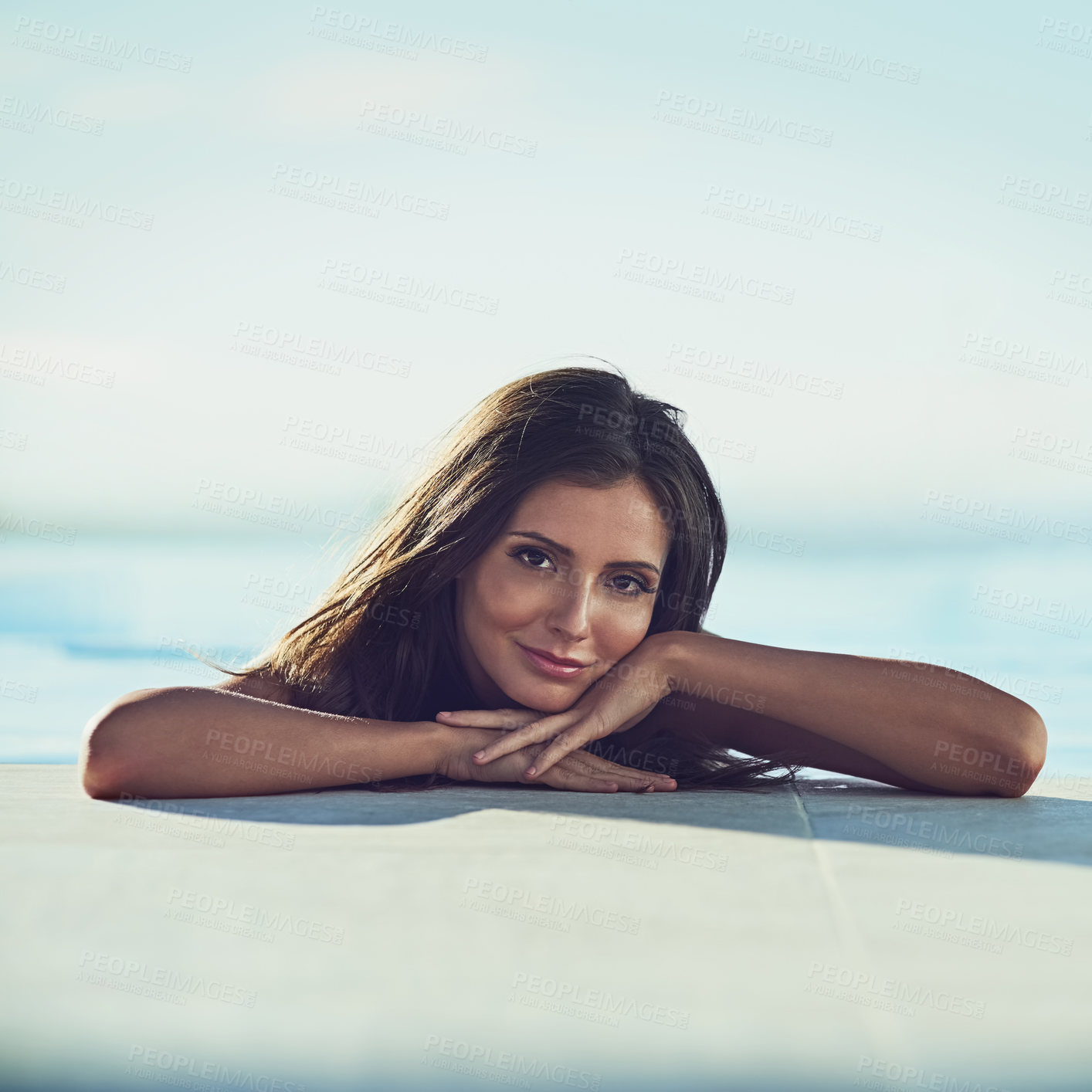 Buy stock photo Portrait of a beautiful young woman leaning at the edge of a swimming pool on a sunny day