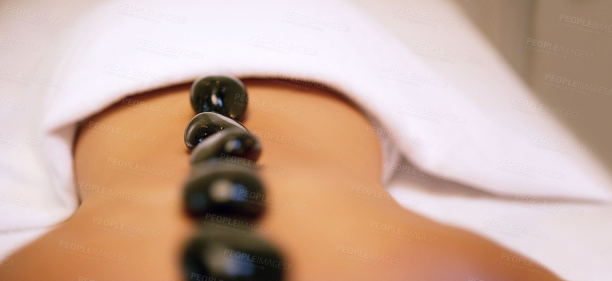 Buy stock photo Spa, treatment and rock on back for woman, stress relief and pain or muscle tension help. Relax, luxury and zen for body care and wellness service, holistic and beauty salon with stones for detox