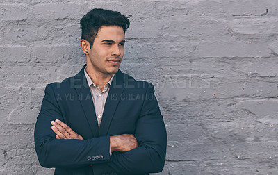Buy stock photo Cropped shot of a handsome young businessman standing against a face brick wall with his arms folded