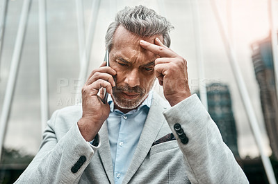 Buy stock photo Shot of a mature businessman looking stressed out while talking on a cellphone in the city