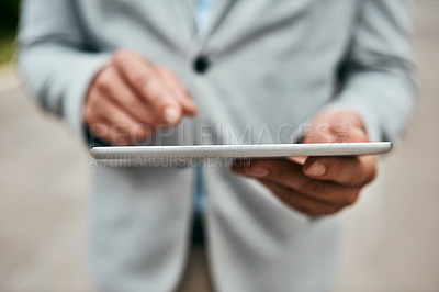 Buy stock photo Closeup shot of an unrecognizable businessman using a digital tablet outdoors