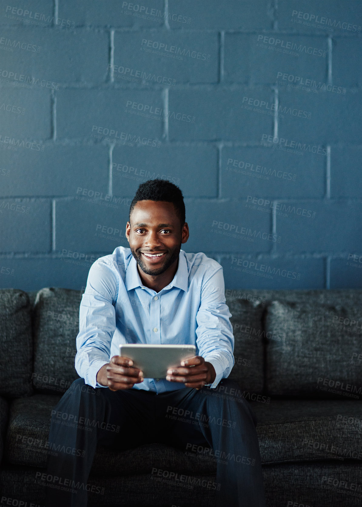 Buy stock photo Portrait, business and black man on couch, tablet and smile with internet, brick wall and connection. Face, African person or employee for consulting agency, technology and planning for sales company