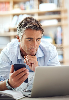 Buy stock photo Cropped shot of a handsome mature man lying on his living room floor using a laptop