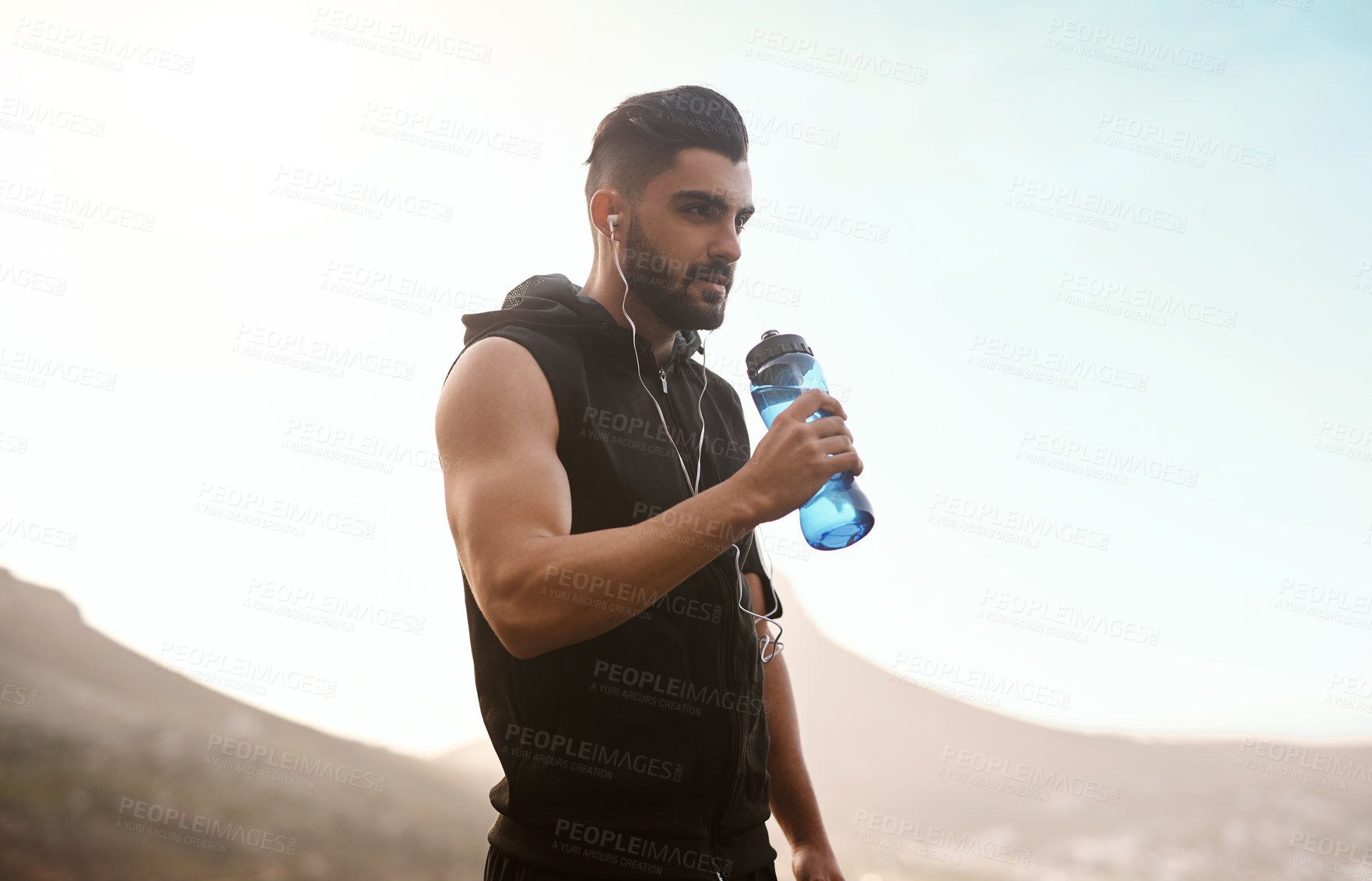 Buy stock photo Shot of a sporty young man drinking water while exercising outdoors