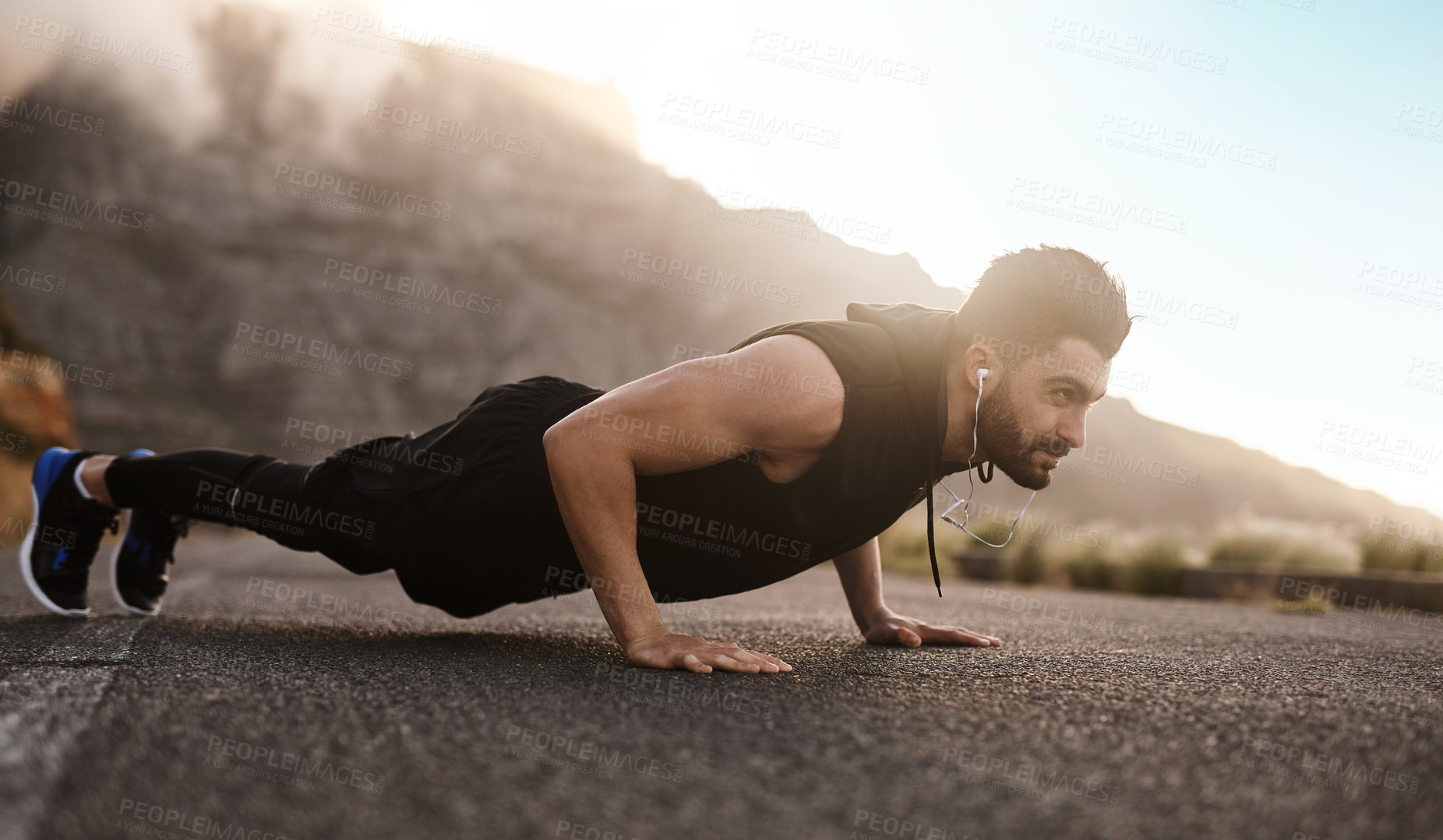 Buy stock photo Shot of a sporty young man doing pushups while exercising outdoors