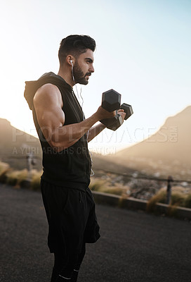 Buy stock photo Shot of a sporty young man exercising with weights outdoors