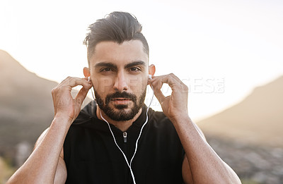 Buy stock photo Portrait of a young man listening to music while exercising outdoors