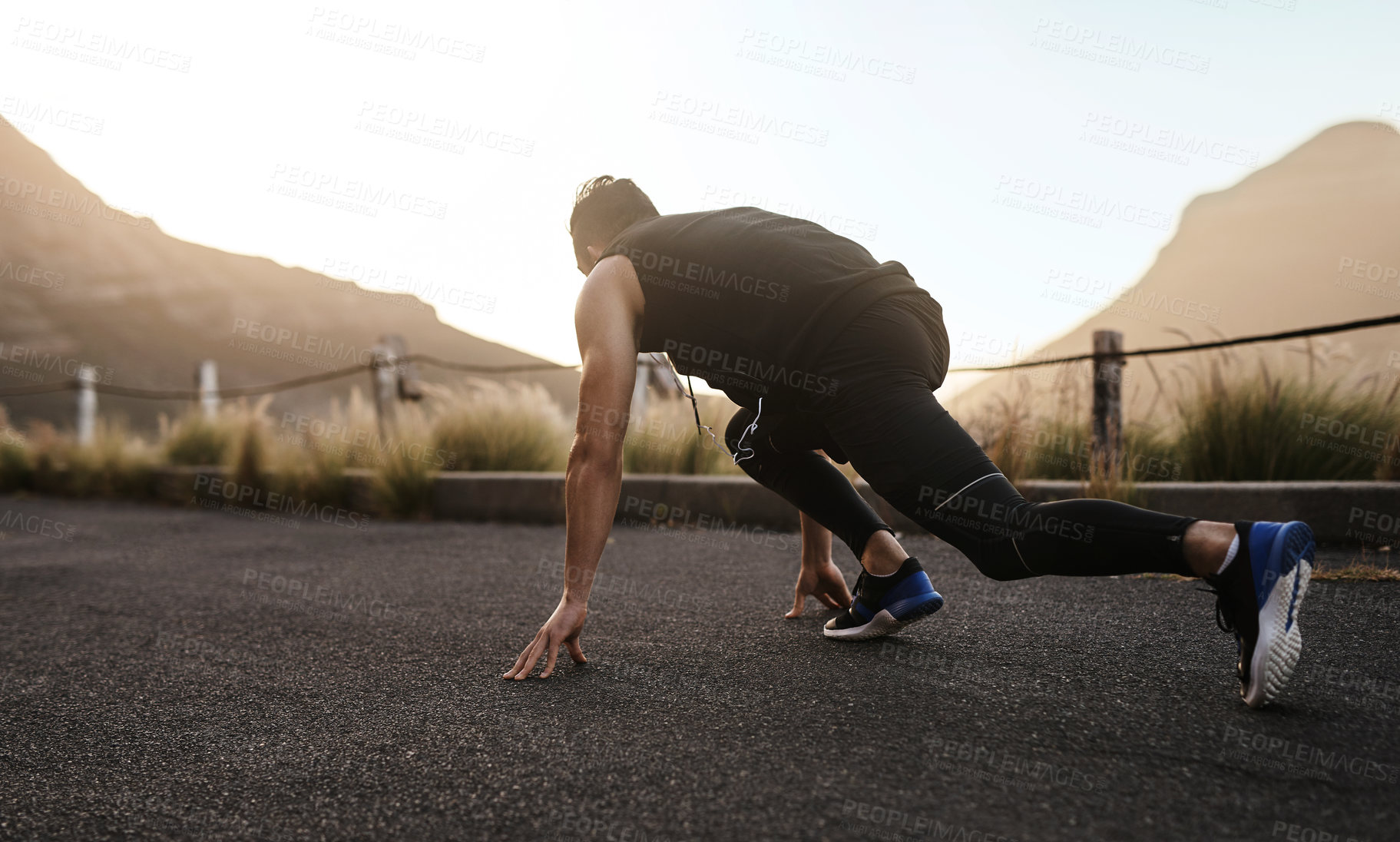 Buy stock photo Rearview shot of a sporty young man in starting position while exercising outdoors