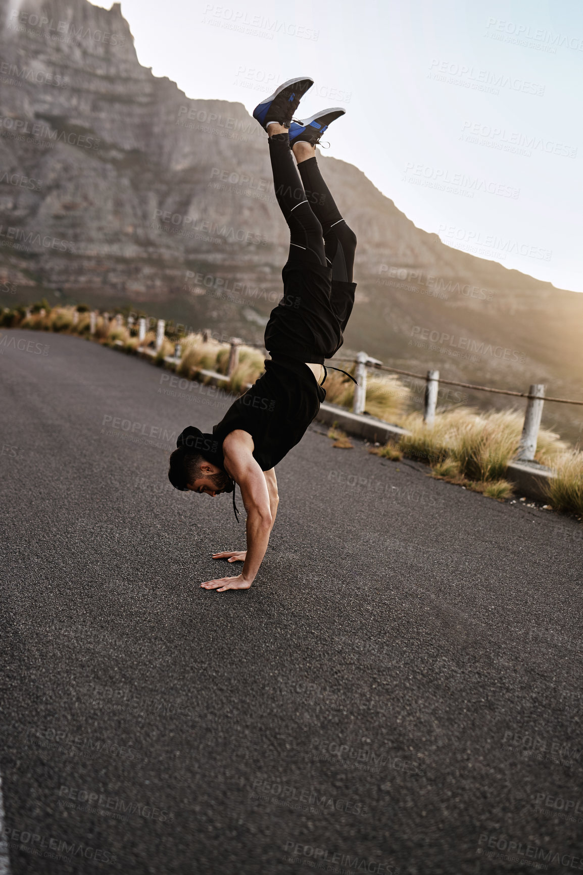 Buy stock photo Shot of a sporty young man doing a handstand while exercising outdoors