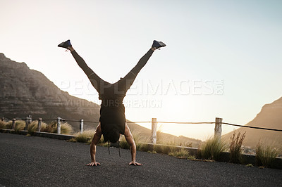 Buy stock photo Shot of a sporty young man doing a handstand while exercising outdoors