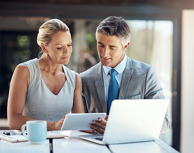 Buy stock photo Shot of a focused mature business couple looking at projections on a tablet in the office to improve their work
