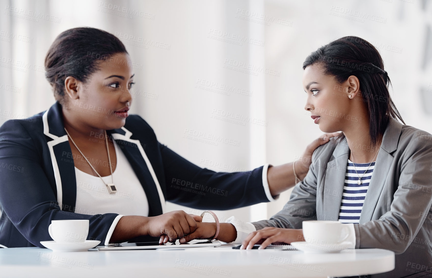 Buy stock photo Cropped shot of an attractive young businesswoman being consoled by a female colleague in their workplace