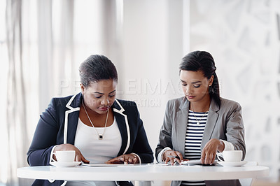 Buy stock photo Cropped shot of two attractive young businesswomen working together behind a desk in their office