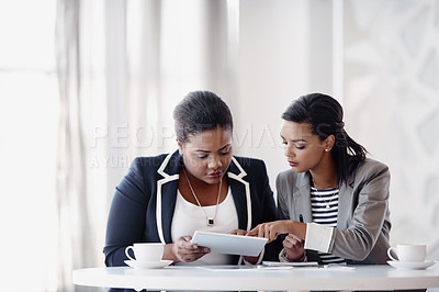 Buy stock photo Cropped shot of two attractive young businesswomen working together behind a desk in their office