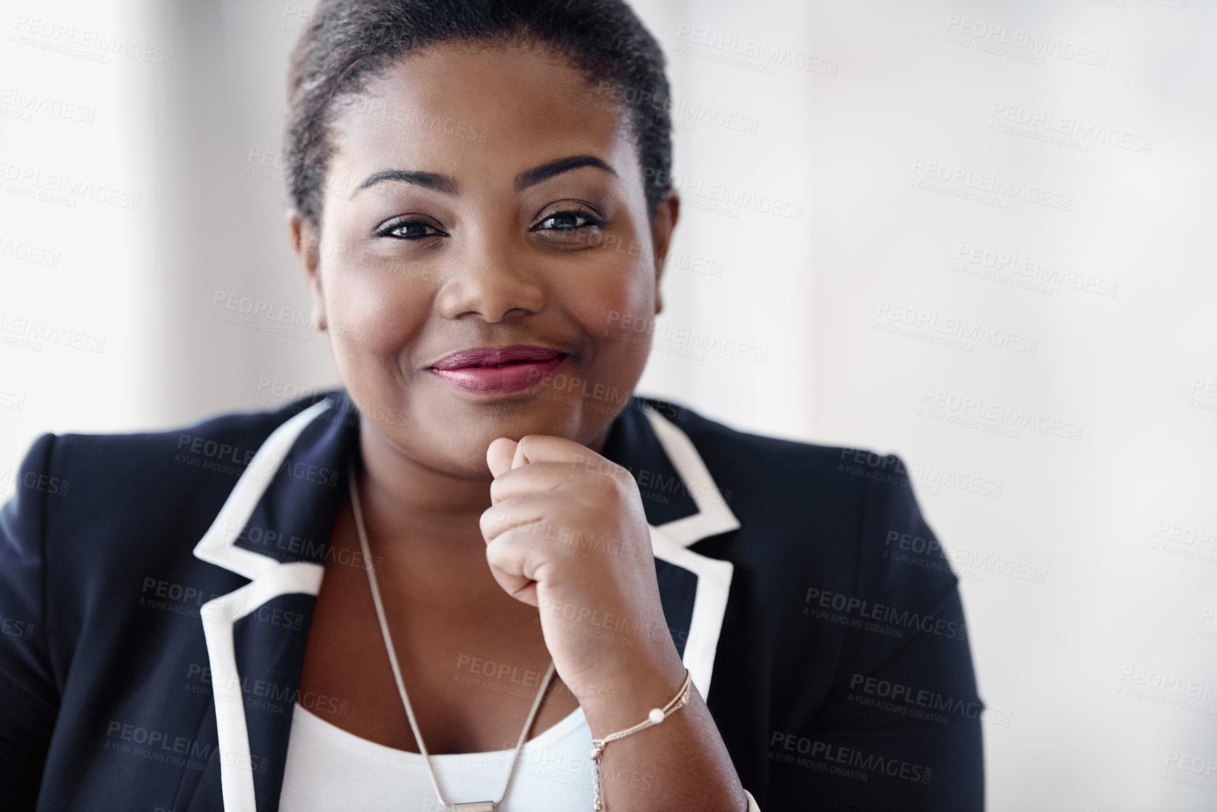 Buy stock photo Cropped portrait of an attractive young businesswoman sitting behind a desk in the office with her hand on her chin