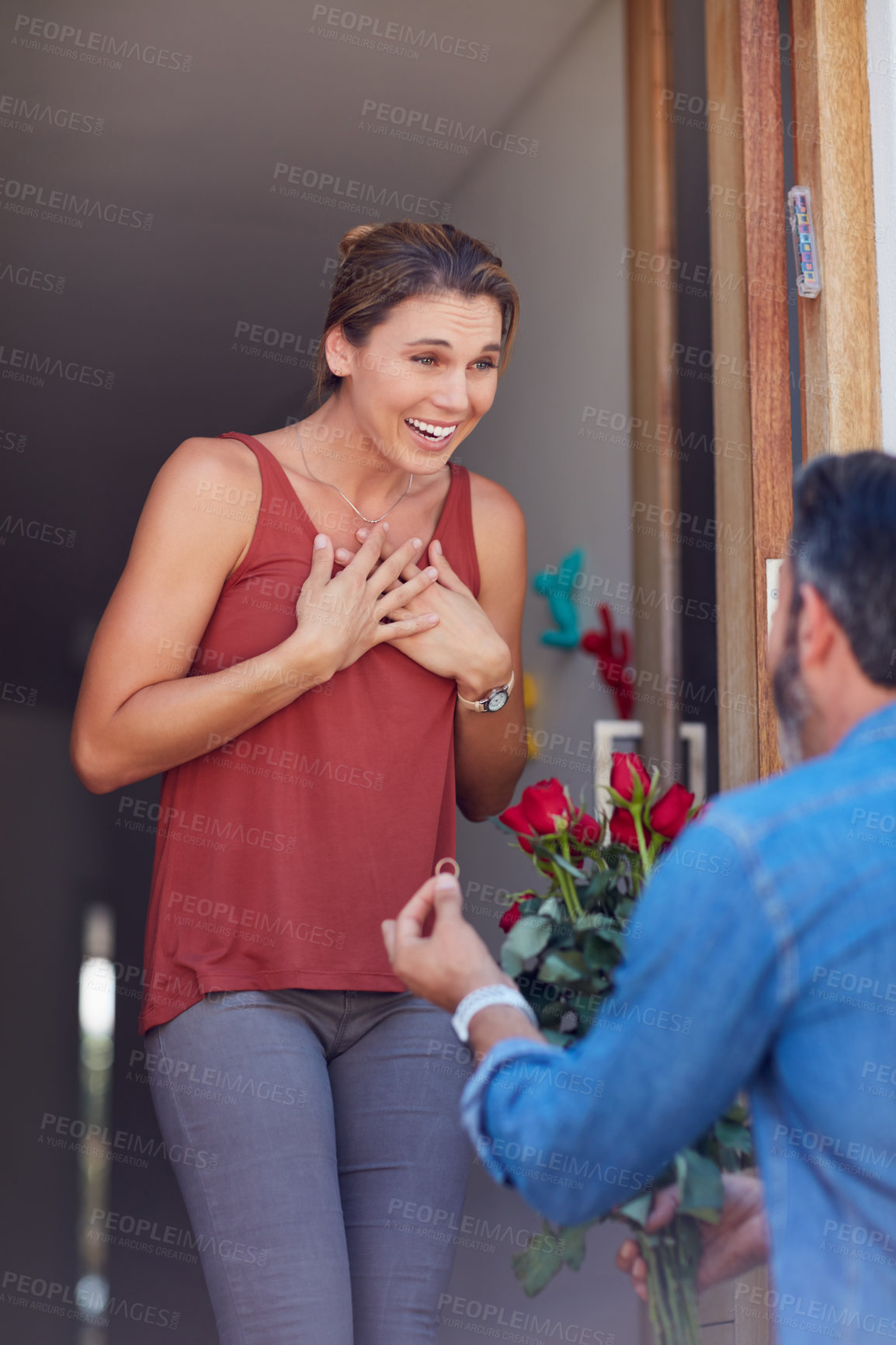 Buy stock photo Cropped shot of an attractive young woman accepting a marriage proposal while standing on her doorway at home