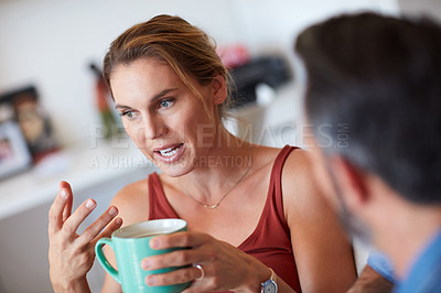 Buy stock photo Cropped shot of an attractive young woman having a serious conversation with her husband while holding a cup of coffee