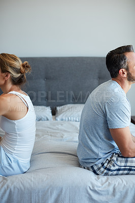 Buy stock photo Cropped shot of an unrecognizable couple sitting back to back after a disagreement in their bedroom