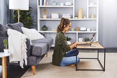 Buy stock photo Full length shot of a beautiful young woman sitting on the floor and using her laptop while relaxing at home
