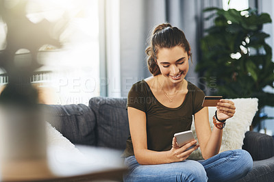 Buy stock photo Shot of a beautiful young woman using her cellphone and credit card to do some online shopping at home