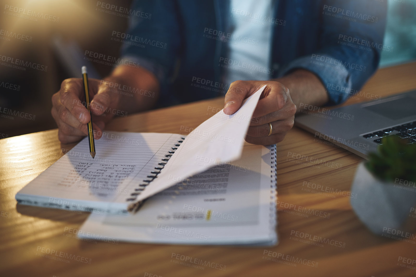 Buy stock photo Shot of an unrecognisable businessman writing notes in a notebook while working late at night in a modern office