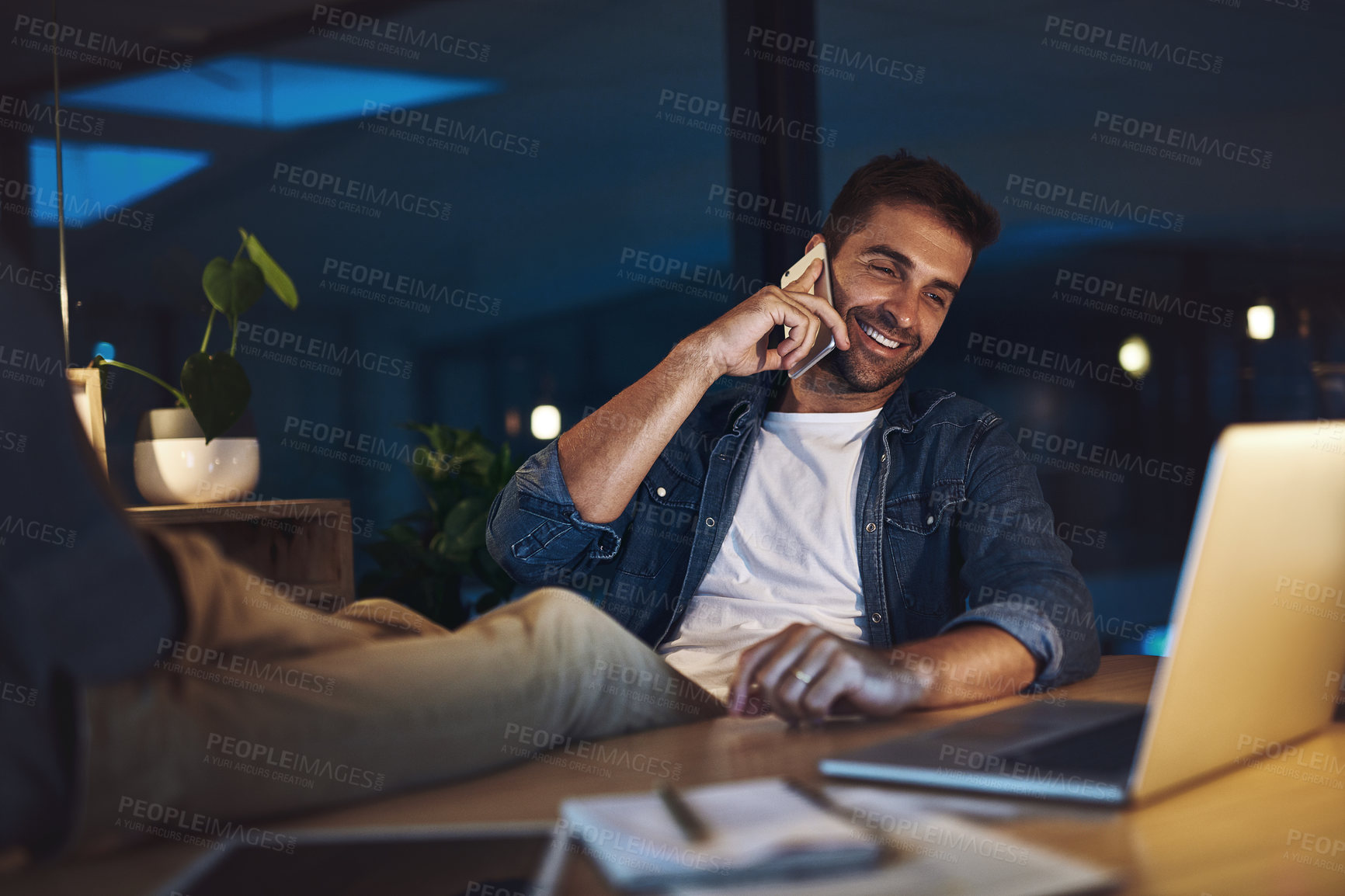 Buy stock photo Relax, office and man with phone call, laptop and smile for contact, connection and night at digital agency. Late, chat and design consultant with smartphone for networking, communication or business