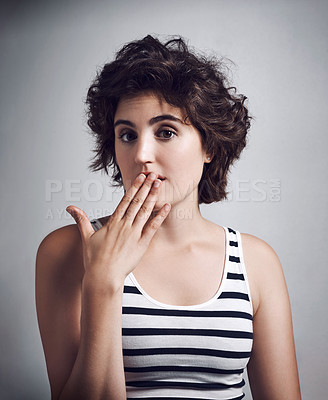 Buy stock photo Studio portrait of an attractive young woman with her hand over her mouth against a grey background