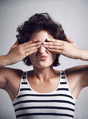 Buy stock photo Studio shot of an attractive young woman covering her eyes with her hands against a grey background