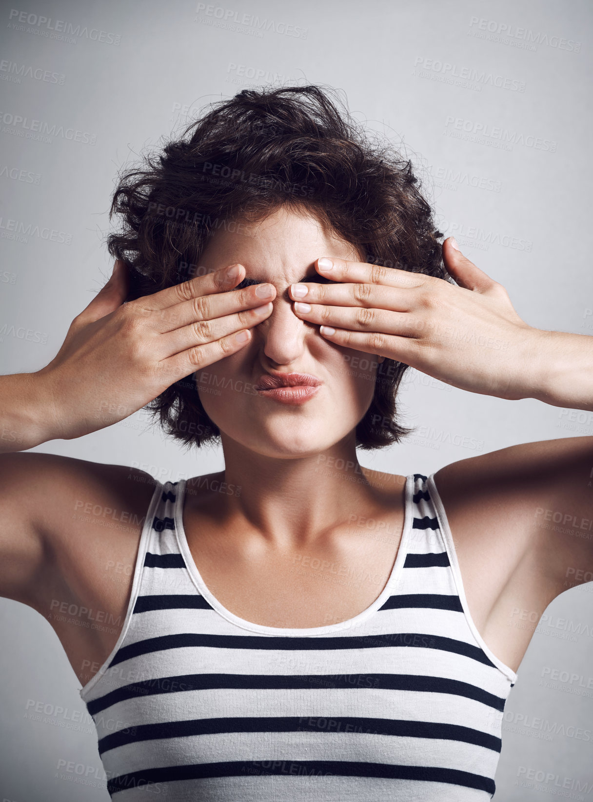 Buy stock photo Studio shot of an attractive young woman covering her eyes with her hands against a grey background