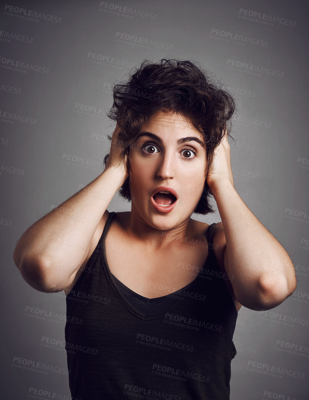 Buy stock photo Studio portrait of an attractive young woman looking shocked while standing against a grey background