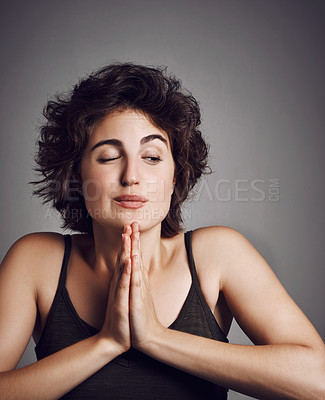 Buy stock photo Studio shot of an attractive young woman with her hands in prayer position against a grey background