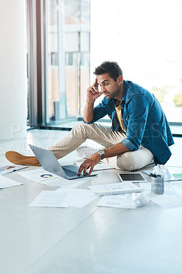 Buy stock photo Shot of a young businessman looking stressed out while working on a floor in an office