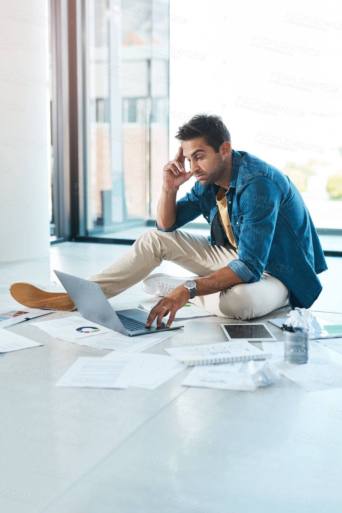 Buy stock photo Shot of a young businessman looking stressed out while working on a floor in an office