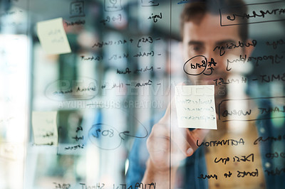 Buy stock photo Shot of a businessman brainstorming with notes on a glass wall in an office