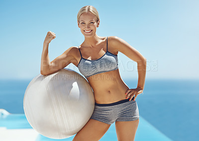 Buy stock photo Cropped shot of an attractive young woman flexing her bicep on an exercise ball by the pool after her workout